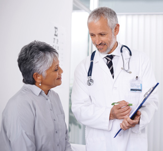 Male doctor showing information to older woman patient in exam room